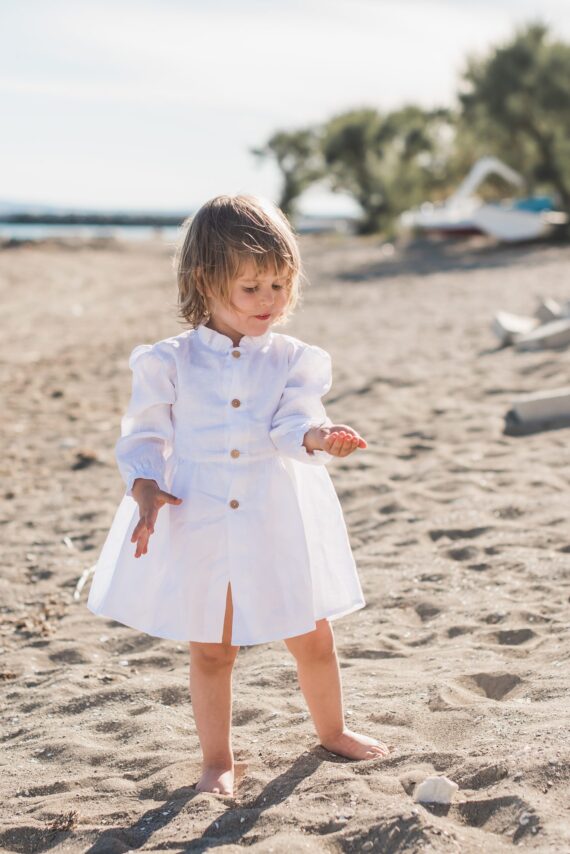 Lanena haljina na djevojčici koja se igra pijeskom na plaži.