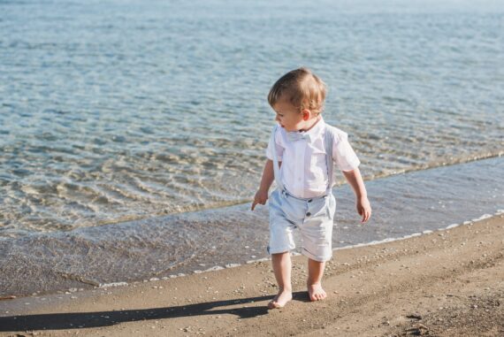Dijete na pješčanoj plaži u odijelu za krštenje Leo.